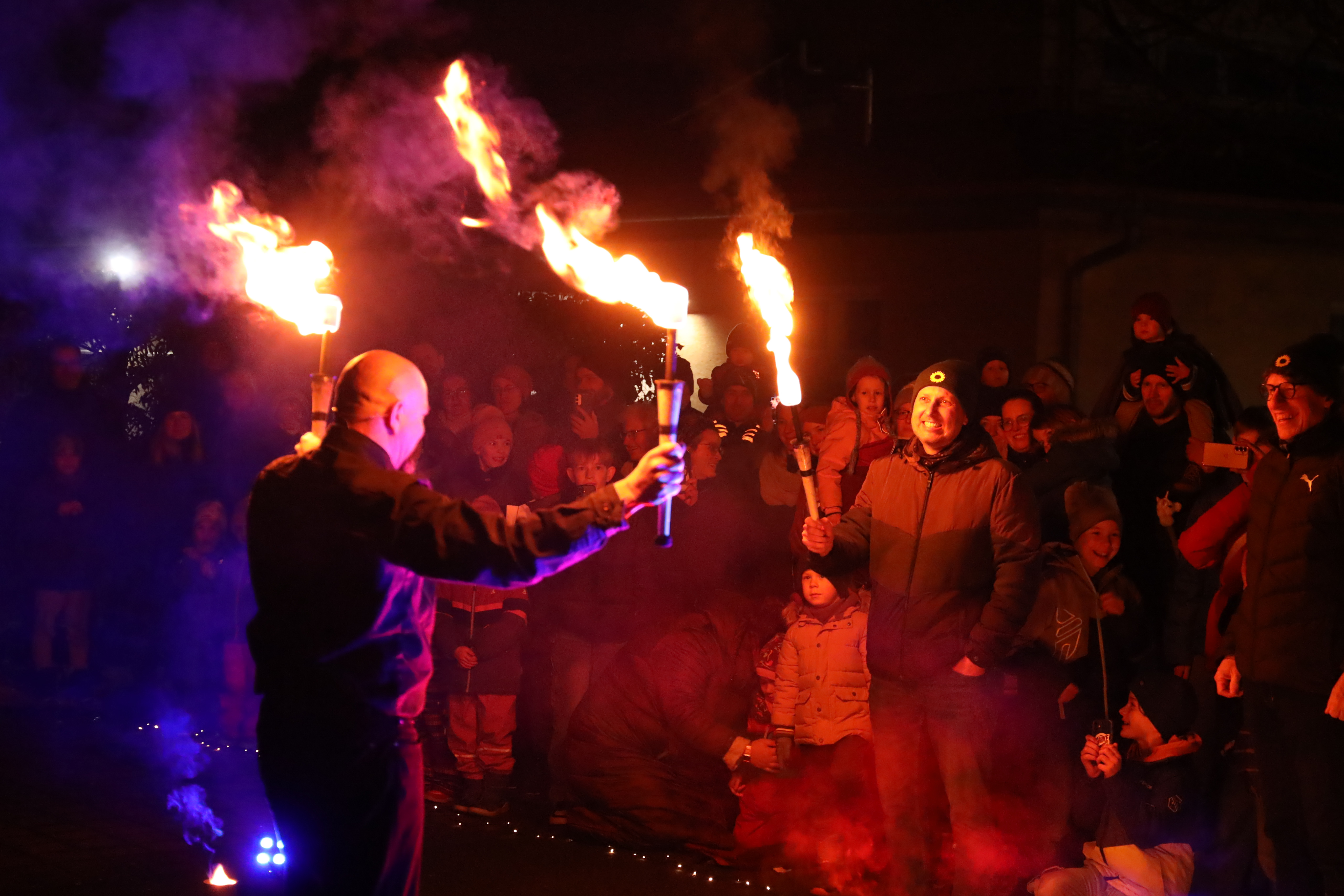 Jens Engelhardt und Matthias Hüttmann übergeben dem Feuerkünstler Perujo zwei Fackeln für das Jonglieren mit Feuerkeulen.